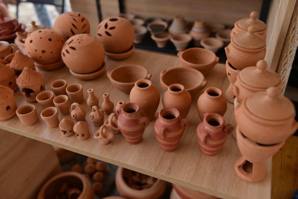 Mesa com diferentes tipos de artesanato lucrativo, como joias, cadernos e vasos de cerâmica